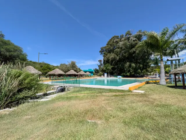 Alberca con palapas, palmeras y caída de agua