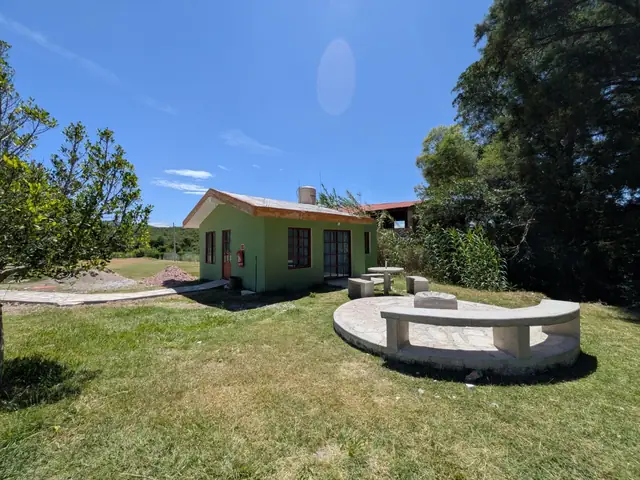 Área exterior de la cabaña con mesa y círculo de bancas