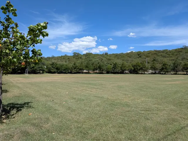 Cancha de fútbol de pasto rodeada de cerros